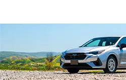silver subaru on gravel road in a green hill scenery
